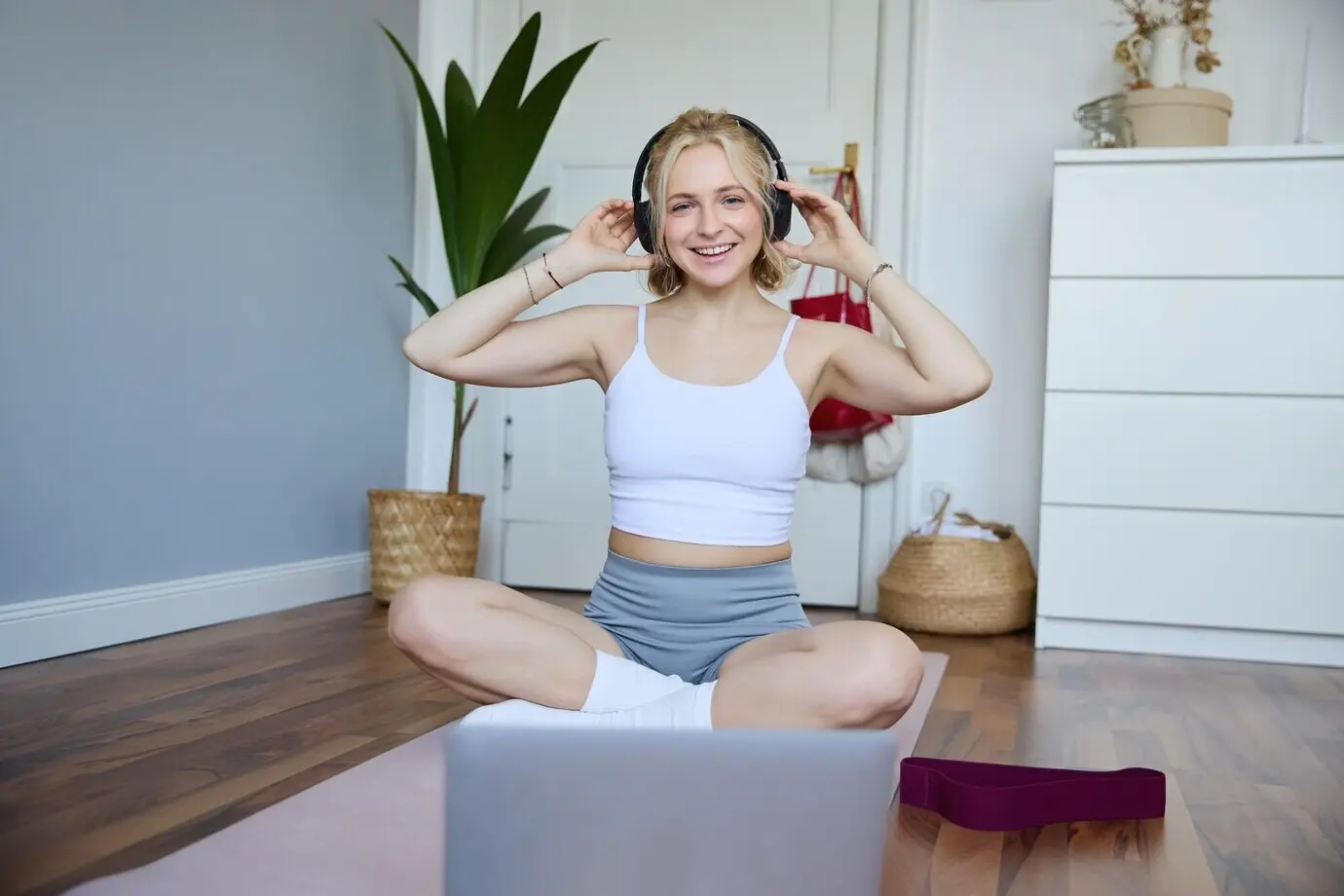 Porträt einer fitten und gesunden jungen Frau mit kabellosen Kopfhörern, die mithilfe eines Online-Videos trainiert.